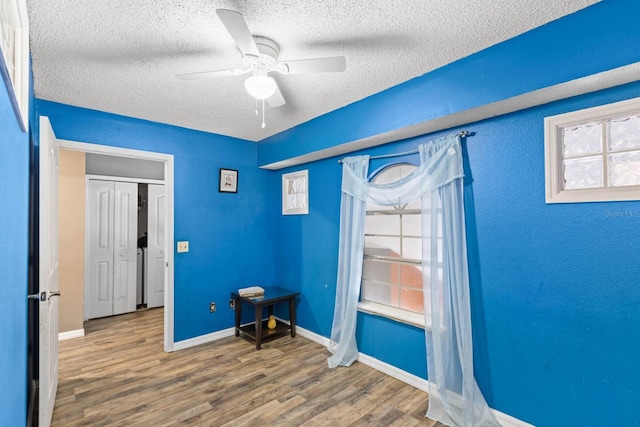 interior space featuring a healthy amount of sunlight, ceiling fan, wood-type flooring, and a textured ceiling