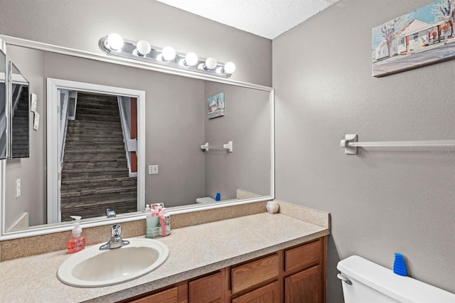 bathroom with vanity, a textured ceiling, and toilet