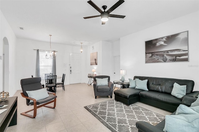 tiled living room with ceiling fan with notable chandelier