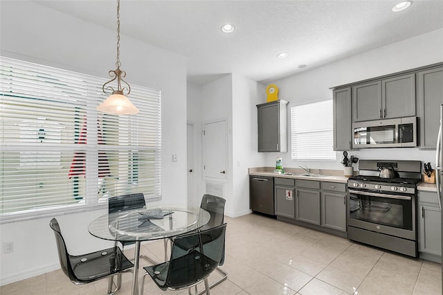 kitchen featuring light tile patterned flooring, gray cabinets, stainless steel appliances, and pendant lighting