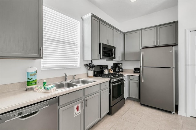 kitchen featuring stainless steel appliances, plenty of natural light, sink, gray cabinets, and light tile patterned floors