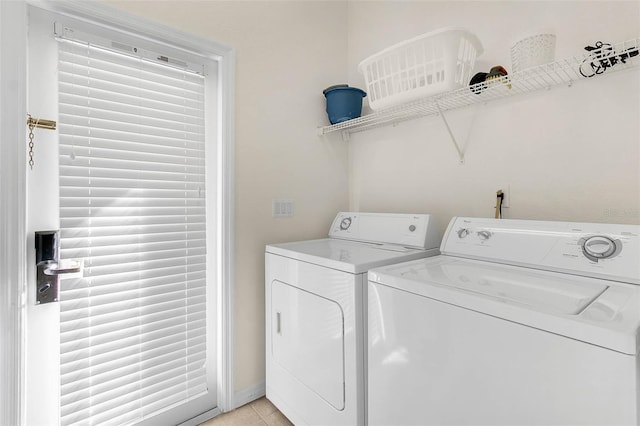 clothes washing area featuring light tile patterned floors and washer and clothes dryer