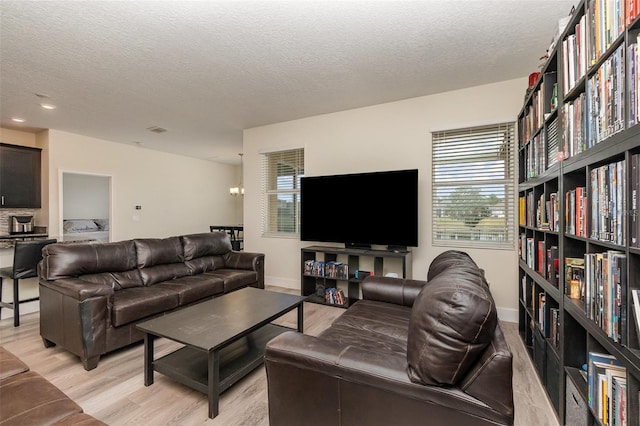 living room featuring light hardwood / wood-style floors, a textured ceiling, and an inviting chandelier