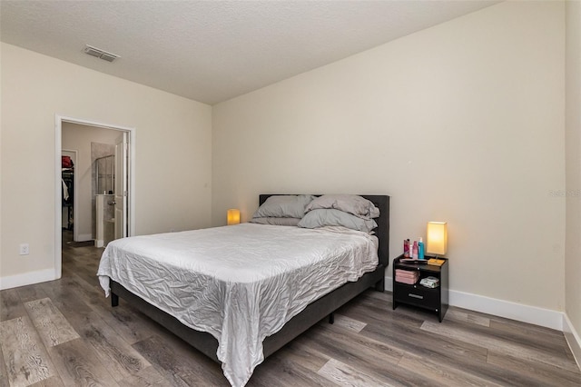 bedroom with dark hardwood / wood-style floors and a walk in closet