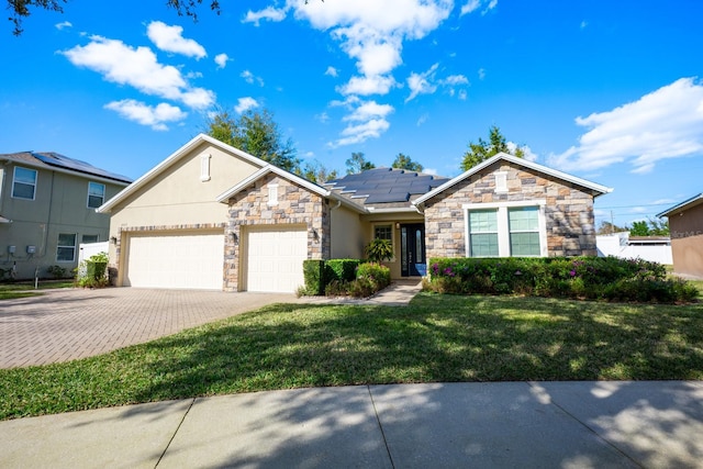 view of front of property with a garage, a front yard, and solar panels