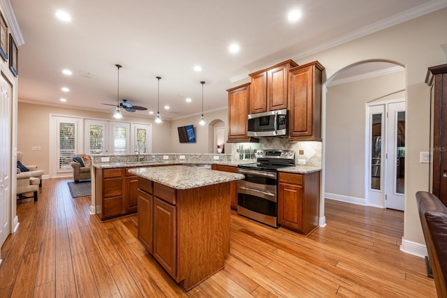 kitchen featuring decorative light fixtures, light wood-type flooring, appliances with stainless steel finishes, kitchen peninsula, and backsplash