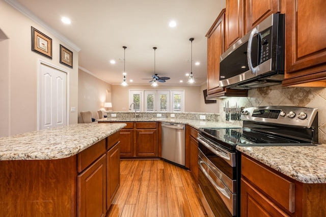 kitchen with sink, crown molding, kitchen peninsula, pendant lighting, and stainless steel appliances