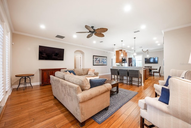 living room featuring crown molding, light hardwood / wood-style flooring, and ceiling fan