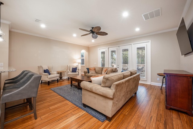 living room with ornamental molding, ceiling fan, and light wood-type flooring