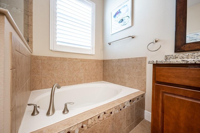 bathroom featuring vanity and a relaxing tiled tub