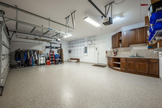 garage featuring a garage door opener, electric panel, and sink