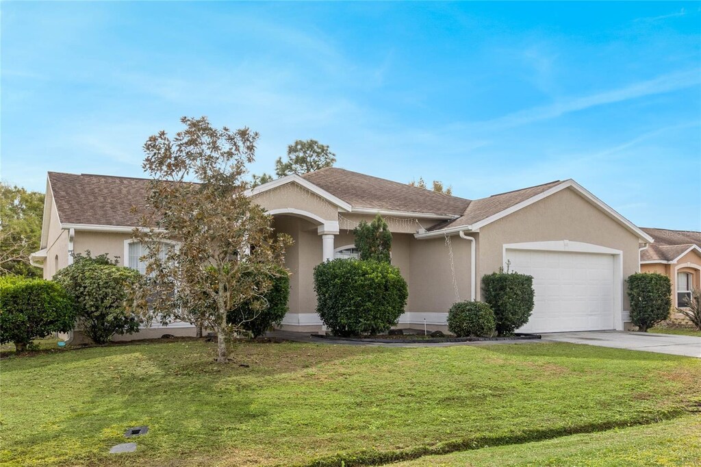 63 York Ct, Kissimmee, FL 34758 - ranch-style house featuring a garage, driveway, stucco siding, and a front yard