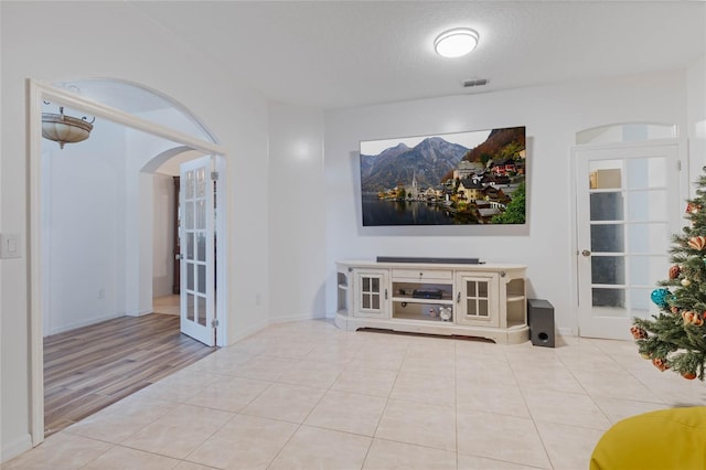 tiled living room featuring a textured ceiling and french doors