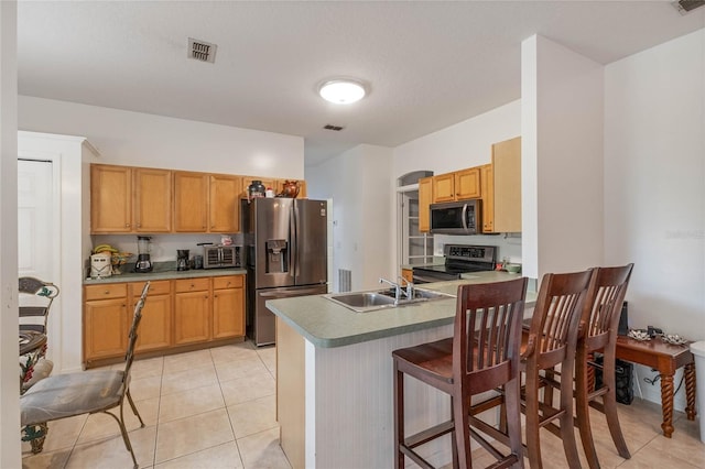 kitchen featuring sink, kitchen peninsula, stainless steel appliances, a breakfast bar area, and light tile patterned flooring