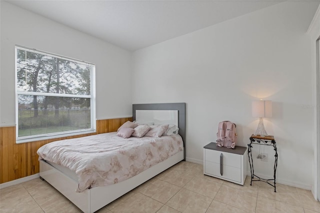 bedroom with light tile patterned flooring and wooden walls