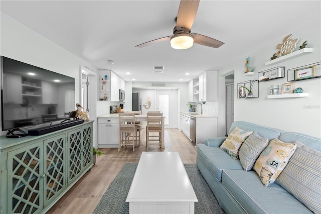 living room featuring sink, ceiling fan, and light wood-type flooring