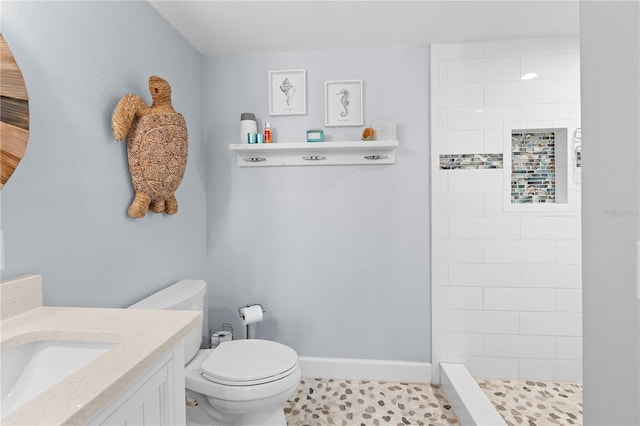 bathroom with vanity, a tile shower, tile patterned floors, and toilet