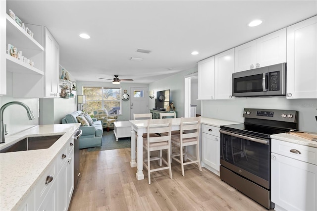 kitchen featuring white cabinetry, sink, stainless steel appliances, and light stone countertops