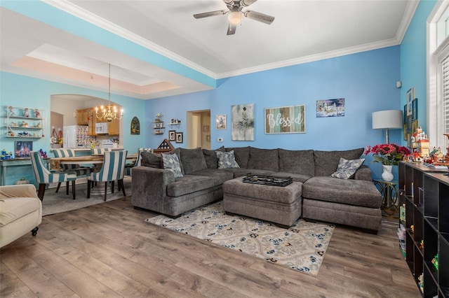 living room with ceiling fan with notable chandelier, hardwood / wood-style floors, crown molding, and a tray ceiling