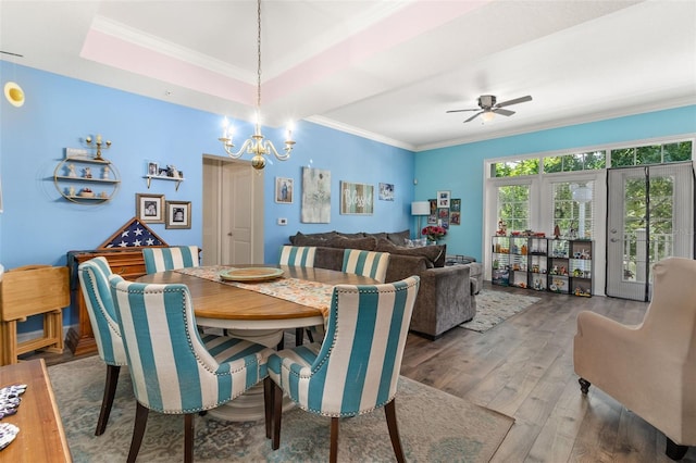 dining space featuring hardwood / wood-style flooring, ceiling fan with notable chandelier, and crown molding