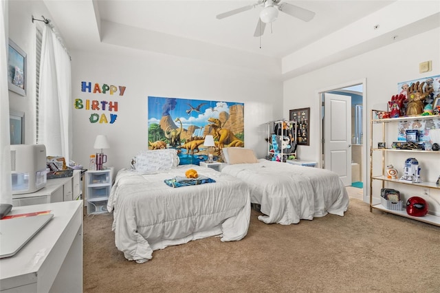 carpeted bedroom with ceiling fan and a raised ceiling