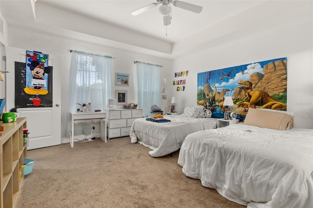 carpeted bedroom with ceiling fan and a raised ceiling