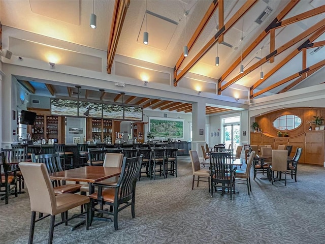 carpeted dining room with indoor bar, beam ceiling, and high vaulted ceiling