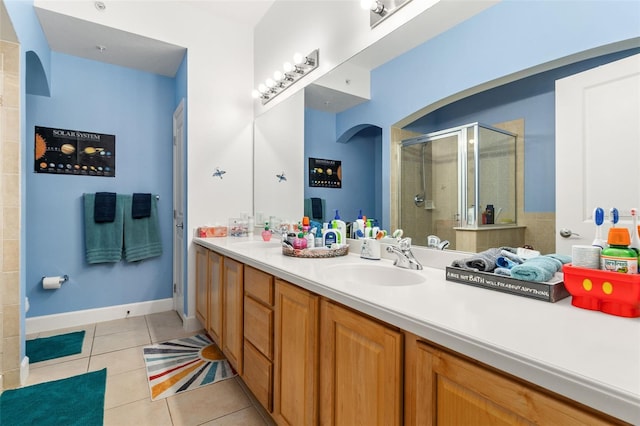 bathroom with a sink, tile patterned flooring, a shower stall, and double vanity