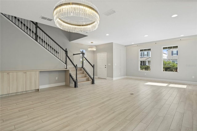 unfurnished living room featuring a chandelier and light hardwood / wood-style floors