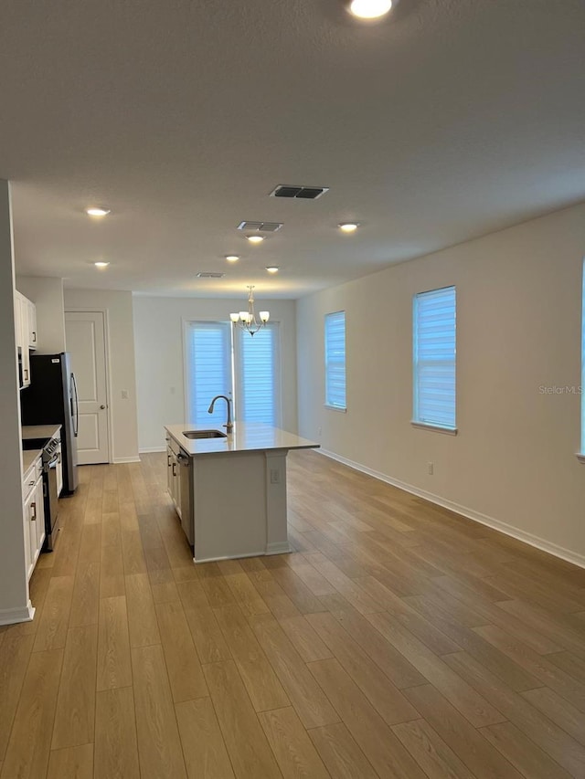 kitchen with sink, white cabinetry, light hardwood / wood-style flooring, an island with sink, and stainless steel appliances