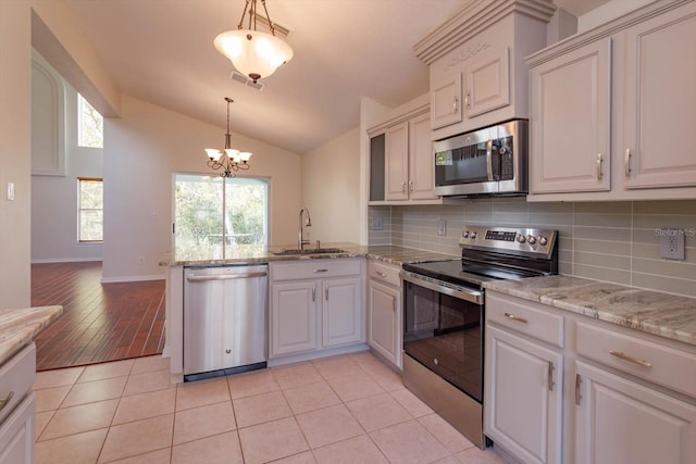 kitchen featuring vaulted ceiling, sink, white cabinetry, light tile patterned floors, and stainless steel appliances