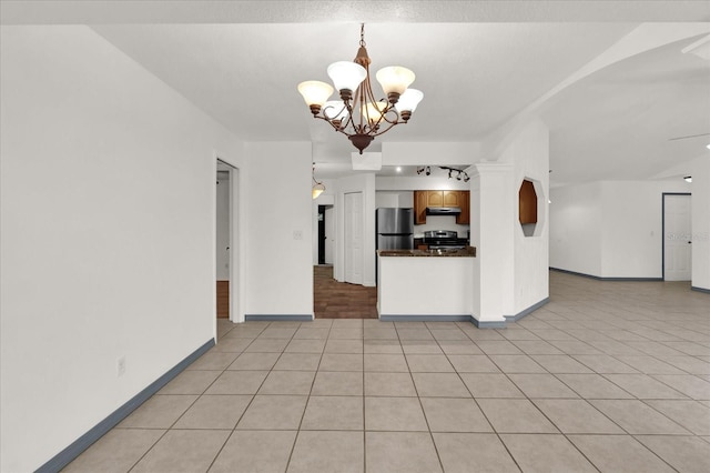 kitchen with a notable chandelier, stainless steel appliances, decorative light fixtures, and light tile patterned floors