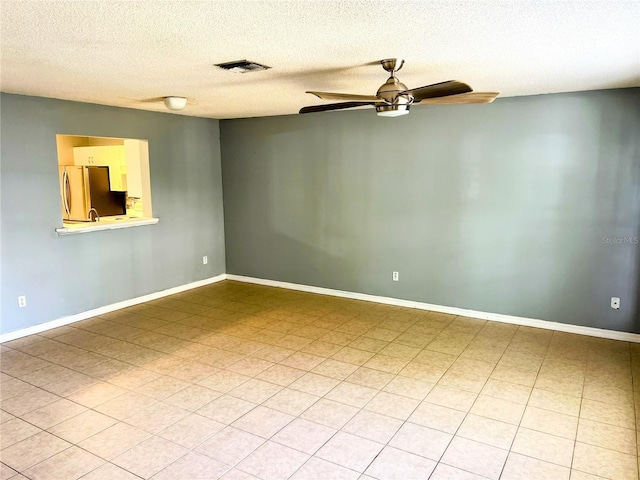 tiled empty room with ceiling fan and a textured ceiling