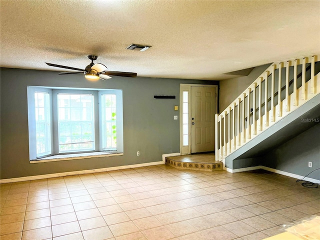 entrance foyer with light tile patterned flooring, ceiling fan, and a textured ceiling