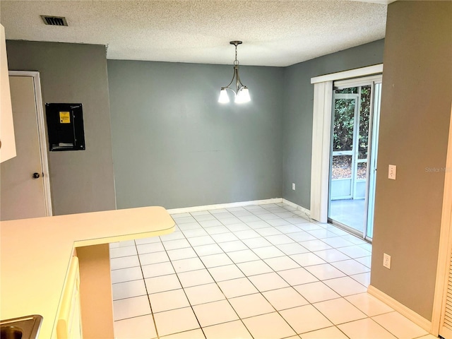 unfurnished dining area featuring light tile patterned floors, a textured ceiling, and a notable chandelier