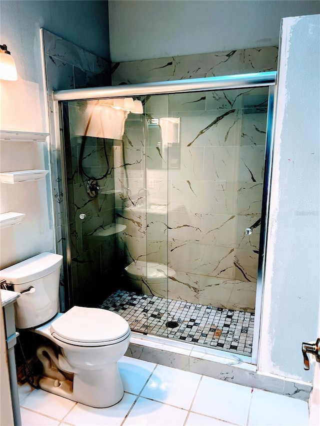 bathroom featuring a shower with shower door, tile patterned floors, and toilet