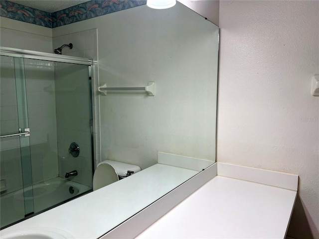 full bathroom featuring toilet, bath / shower combo with glass door, and sink