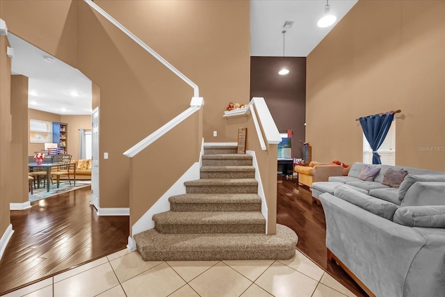 staircase featuring a towering ceiling, a wealth of natural light, and tile patterned floors