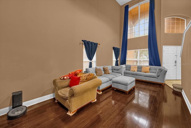 living room with a towering ceiling, a wealth of natural light, and dark hardwood / wood-style flooring