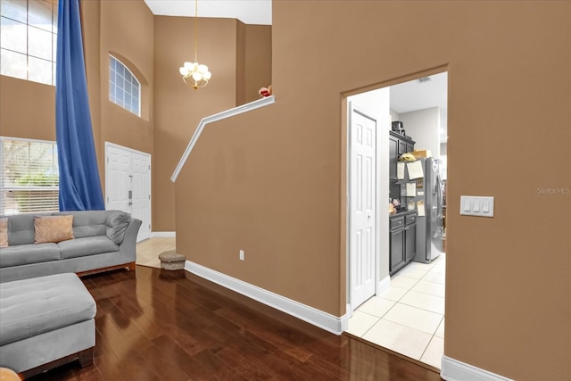 living room with a towering ceiling, hardwood / wood-style floors, and a notable chandelier