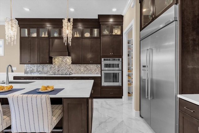 kitchen featuring sink, custom exhaust hood, hanging light fixtures, and appliances with stainless steel finishes