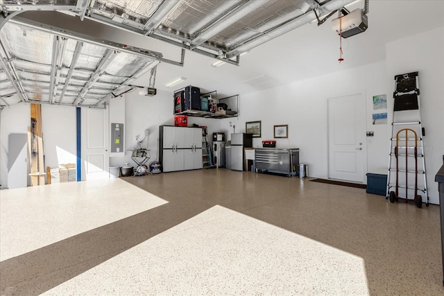 garage featuring electric panel, a garage door opener, and stainless steel refrigerator