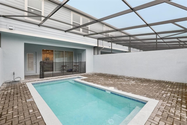 view of pool with glass enclosure and a patio area