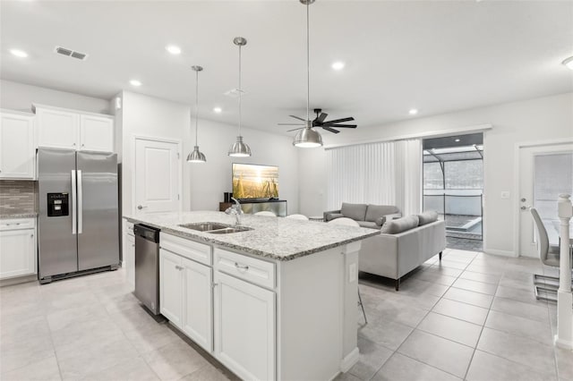 kitchen featuring appliances with stainless steel finishes, white cabinetry, sink, a kitchen island with sink, and light stone counters