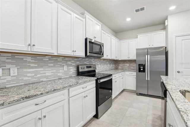 kitchen with white cabinetry, stainless steel appliances, and light stone counters