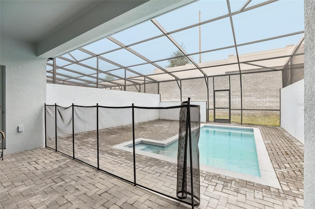 view of swimming pool with a jacuzzi, a patio area, and glass enclosure