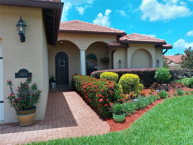 entrance to property featuring a tile roof and stucco siding