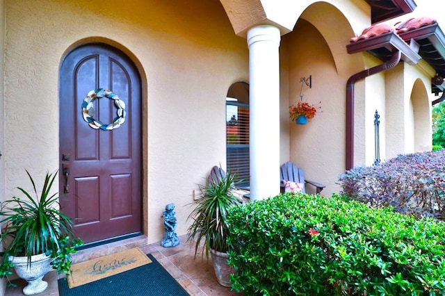 view of exterior entry featuring a tiled roof and stucco siding