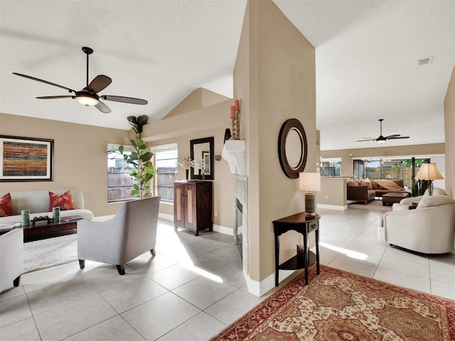 living room with a fireplace, light tile patterned floors, ceiling fan, and vaulted ceiling