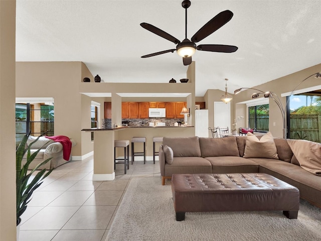 tiled living room with ceiling fan and lofted ceiling